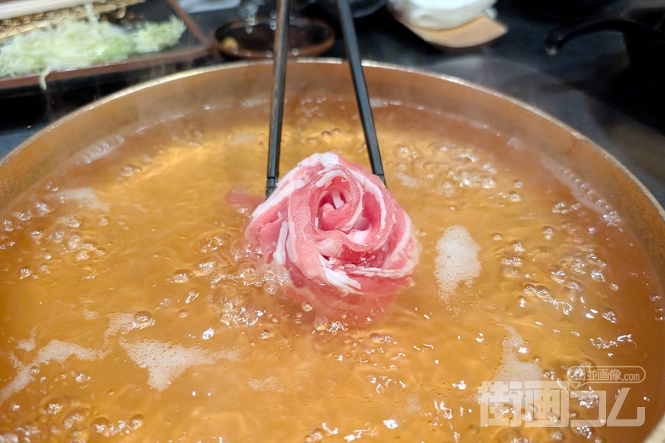 中央に薔薇の花のように盛り付けられたバラ肉をスタッフさんが鍋に入れる