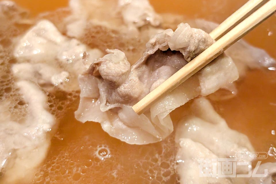 鍋に浮かぶ黒豚バラ肉を箸リフト