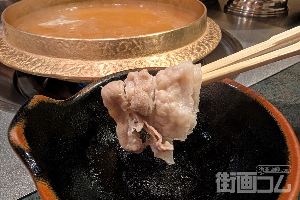 黒豚バラ肉最後の一枚を取り皿で箸リフト(背景に鍋)