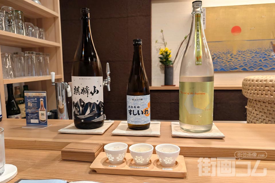 飲み比べセット（３つのお猪口と、その後ろに３種の日本酒の瓶）