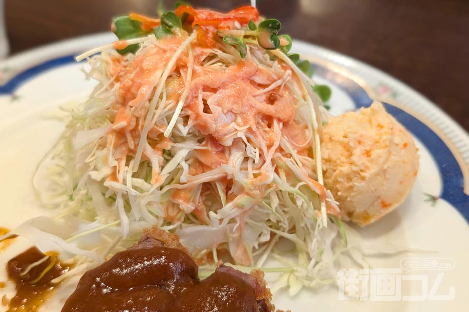 ヘレビーフカツに添えられた千切りキャベツ（ドレッシングがかかっている）とポテトサラダ