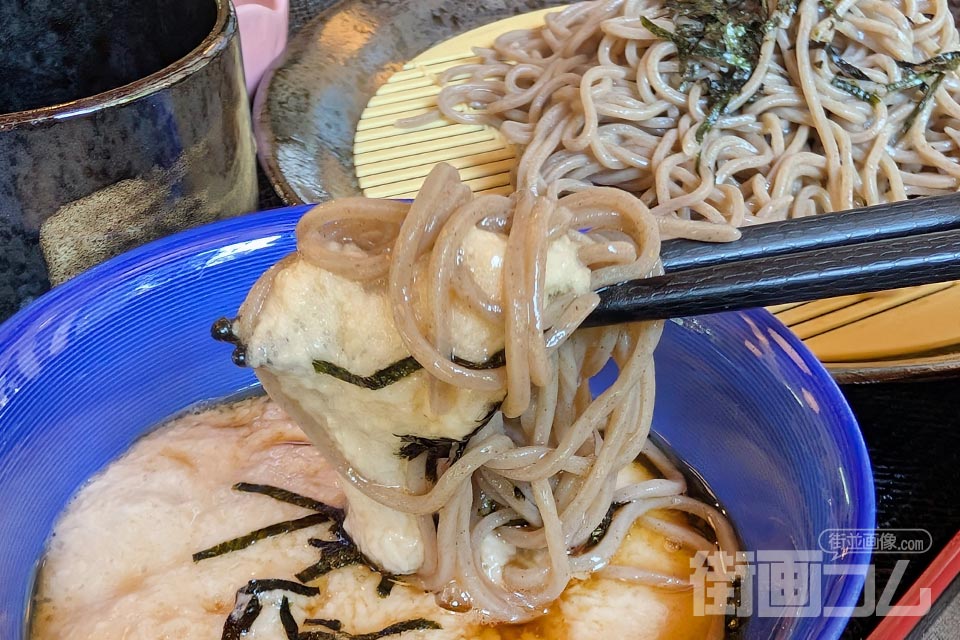 とろろを絡めたそばを箸で持ち上げたところ