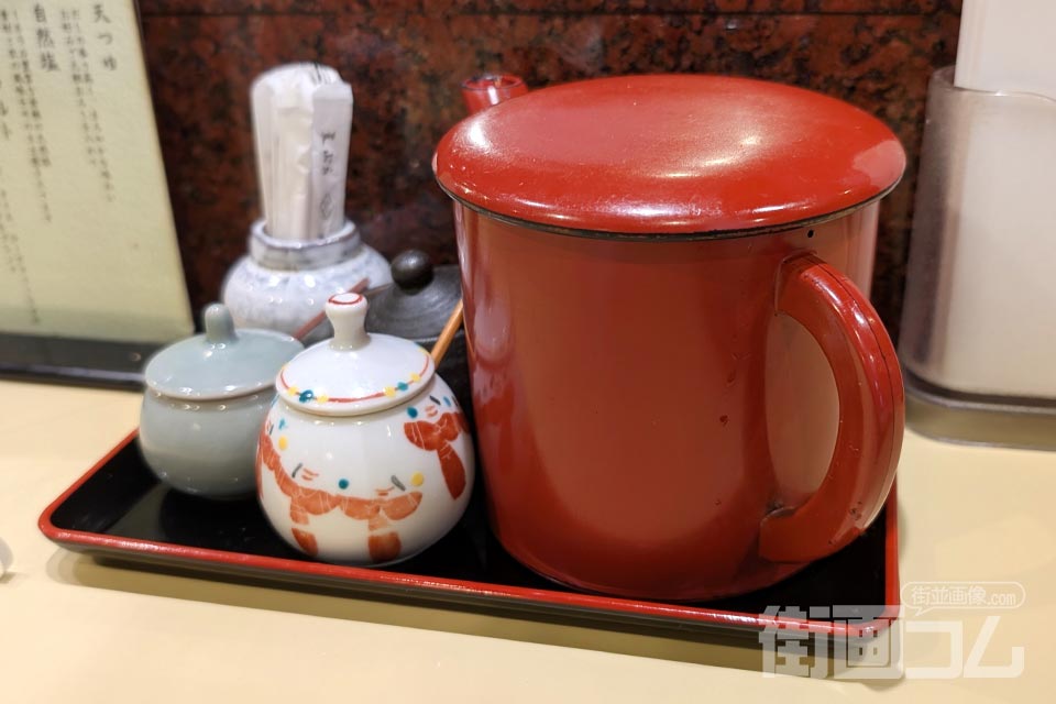 カウンターに置かれた朱塗りの天つゆの器と薬味入れ