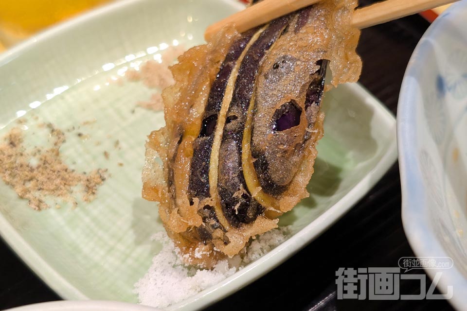 扇状に切り込みを入れた茄子の天ぷらに自然塩をつける