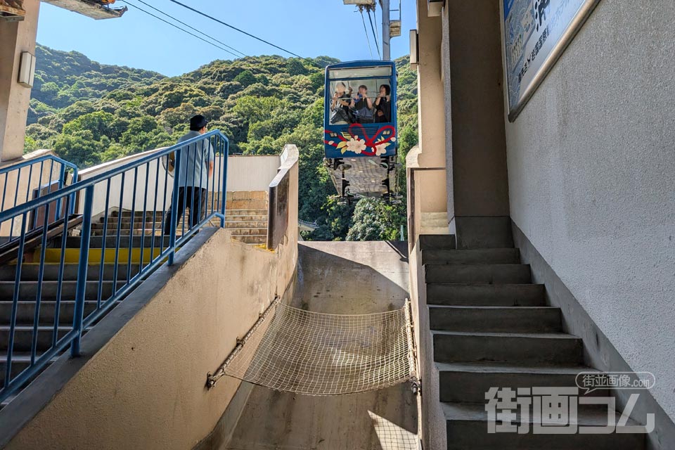 山麓駅のホームから見上げるワイヤーとゴンドラ